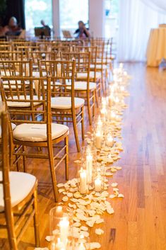 rows of chairs lined up with candles and petals on the floor in front of them