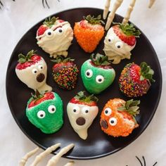 halloween treats on a black plate with strawberries and carrots