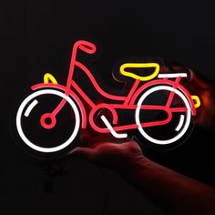 a hand holding a neon sign with a bicycle on it's front and back