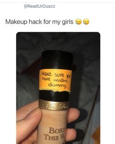 a person holding up a tube of makeup