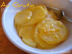 a white bowl filled with sliced bananas on top of a wooden table next to a spoon