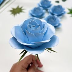 a person is holding some paper flowers on a table