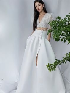 a woman standing in front of a plant wearing a white dress