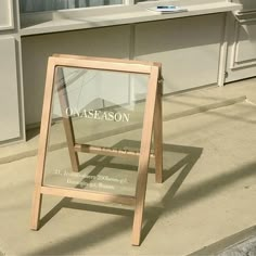 a wooden sign sitting on the side of a road next to a building with windows