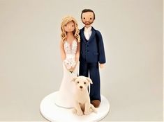 a wedding cake topper with a bride and groom next to a dog on a white plate