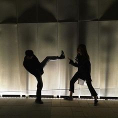 two people standing in front of a wall with their legs spread out and one person holding something