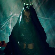 a woman dressed in dark clothing and demon makeup