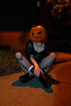 a woman sitting on the ground with her legs crossed, wearing a pumpkin hat and stockings