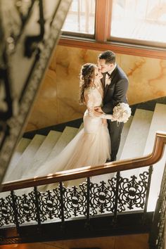 a bride and groom are standing on the stairs