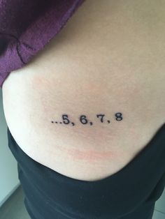 the back of a woman's stomach with numbers tattooed on it