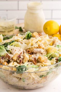 a large bowl filled with pasta salad next to lemons and other ingredients on the counter