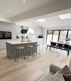 an open floor plan kitchen and living room with white walls, hardwood floors and large windows