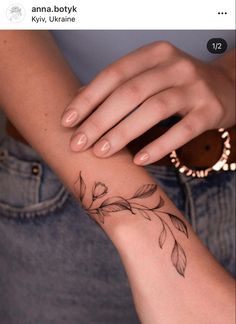 a woman's arm with a feather tattoo on it