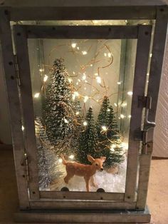 a small christmas tree in a metal box with lights on it and a deer figurine inside