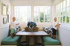 two young children sitting at a table in a room with white walls and black and white flooring