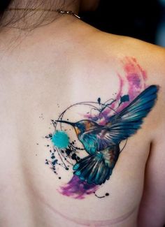 a colorful bird tattoo on the back of a woman's upper arm and shoulder