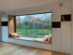 an empty room with a large window and some pillows on the windowsill, in front of a grassy field