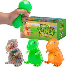 three plastic toys in front of a box and one is holding a green toy dinosaur