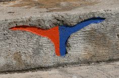 an orange and blue bird painted on the side of a stone wall