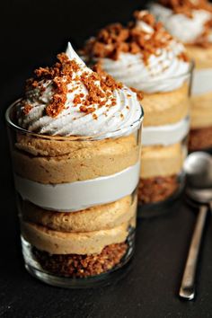 three desserts in glass containers with spoons on the side and one is topped with whipped cream