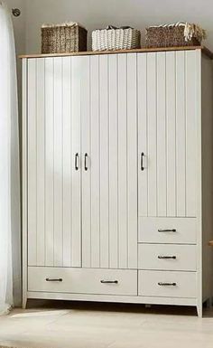 a white armoire with baskets on top of it