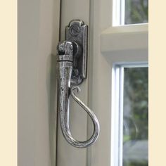 a metal hook on the side of a white door with a window in the background