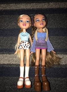 two dolls standing next to each other on the floor in front of carpeted area