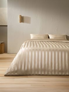 a bed with white and beige striped sheets