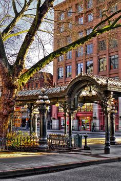 an old - fashioned gazebo sits on the corner of a street in front of tall buildings