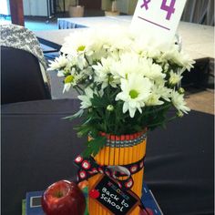 a vase filled with white flowers sitting on top of a table next to an apple