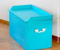 a blue box sitting on top of a hard wood floor next to a white wall