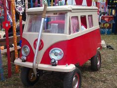 a red and white bus is parked in the grass with other items on display behind it