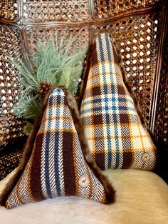 two decorative pillows sitting on top of a bed next to a small pine tree in a basket