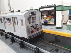 a lego train is on the tracks in front of a toy store with other toys