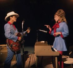 a man and woman standing next to each other in front of microphones on stage