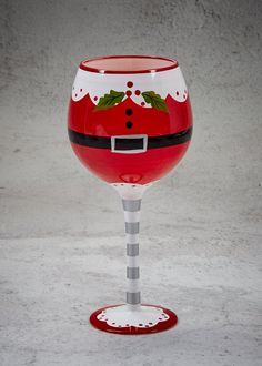 a red wine glass with a santa clause design on the bottom and black stripe around the rim