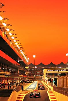 a group of cars driving down a race track at sunset or sunrise with lights on