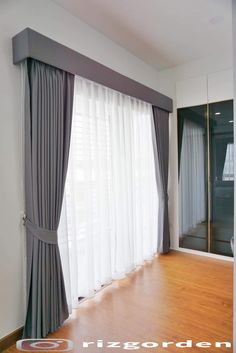 an empty room with wooden floors and curtains