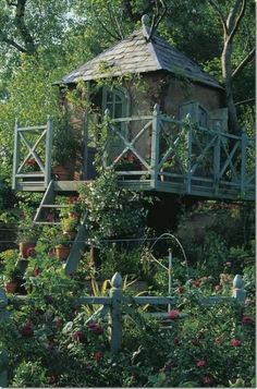 an old house surrounded by flowers and trees