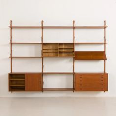 a wooden shelf with drawers and shelves on the side, against a white wall in an empty room