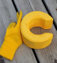 a pair of yellow gloves sitting on top of a wooden bench