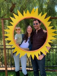 a man, woman and child are standing in front of a sun - shaped photo frame