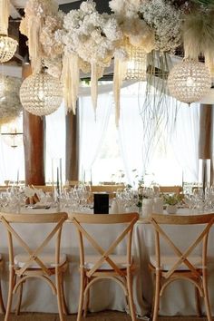 the tables are set with white flowers and chandeliers hanging from the ceiling above them