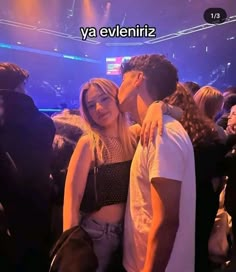 two people kissing each other in front of a crowd at a concert with the words ya evvenirz on it