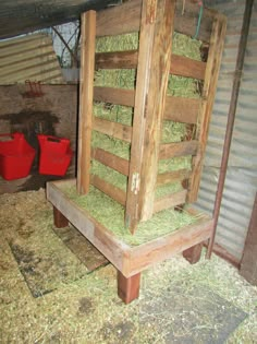 a barn with hay stacked on top of it's sides and two red buckets in the background