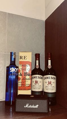 three bottles of wine sitting on top of a wooden shelf next to two boxes and a radio