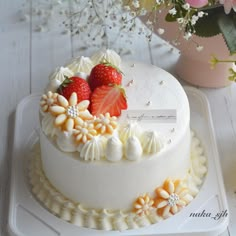 a white cake with strawberries on top and flowers in the middle, sitting on a platter