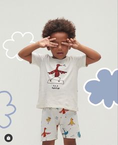 a little boy holding his hands up to his face while standing in front of a white background