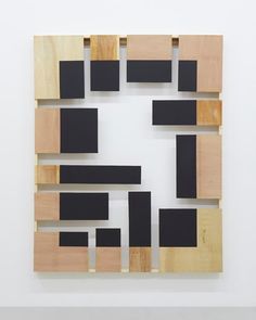 a piece of wood with black squares and rectangles on it in a white room