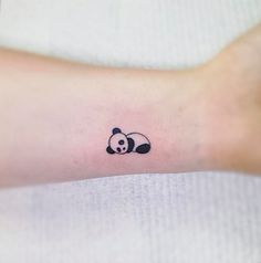 a small panda bear tattoo on the wrist